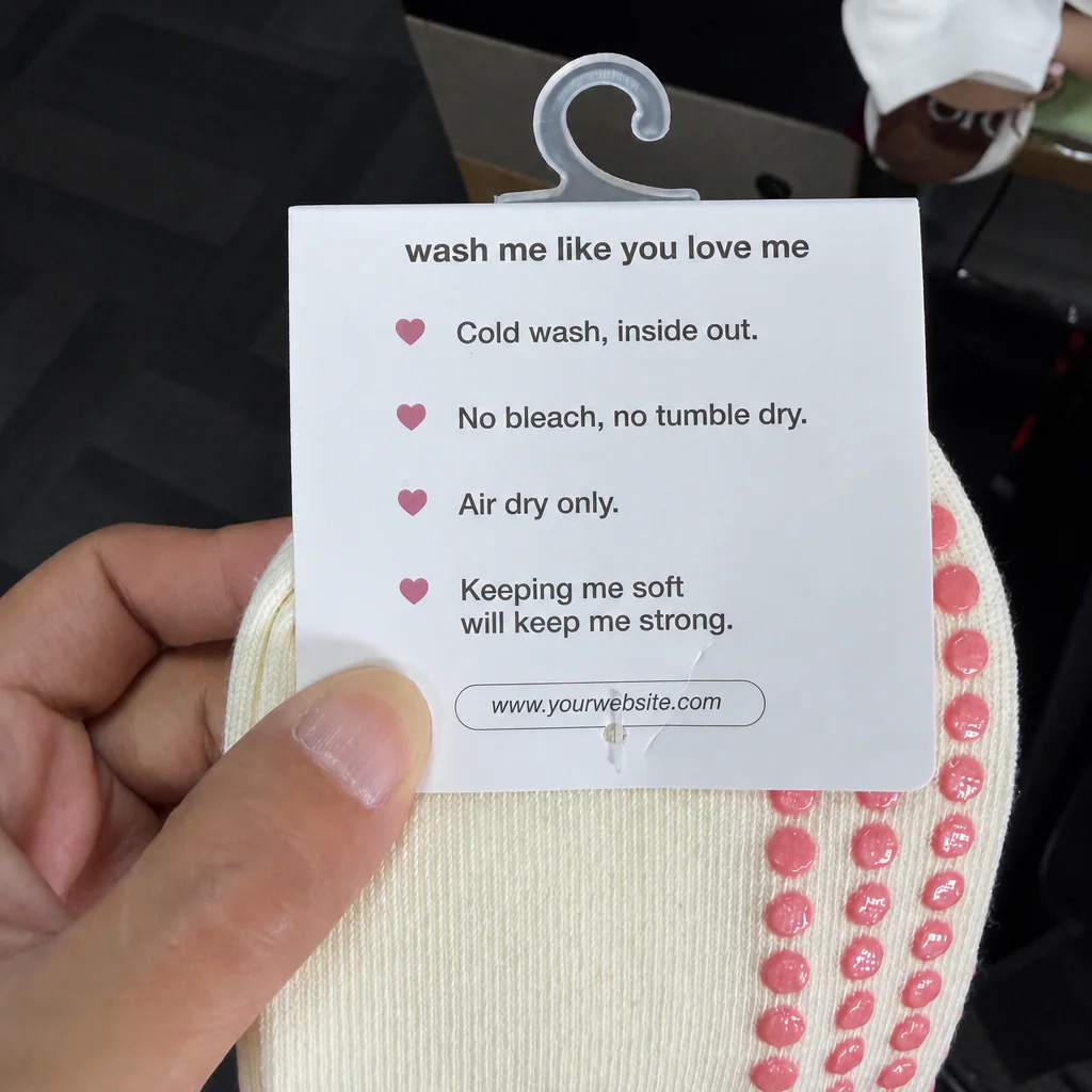 Close view of a physical hanging grip sock header card with placeholder care and website information