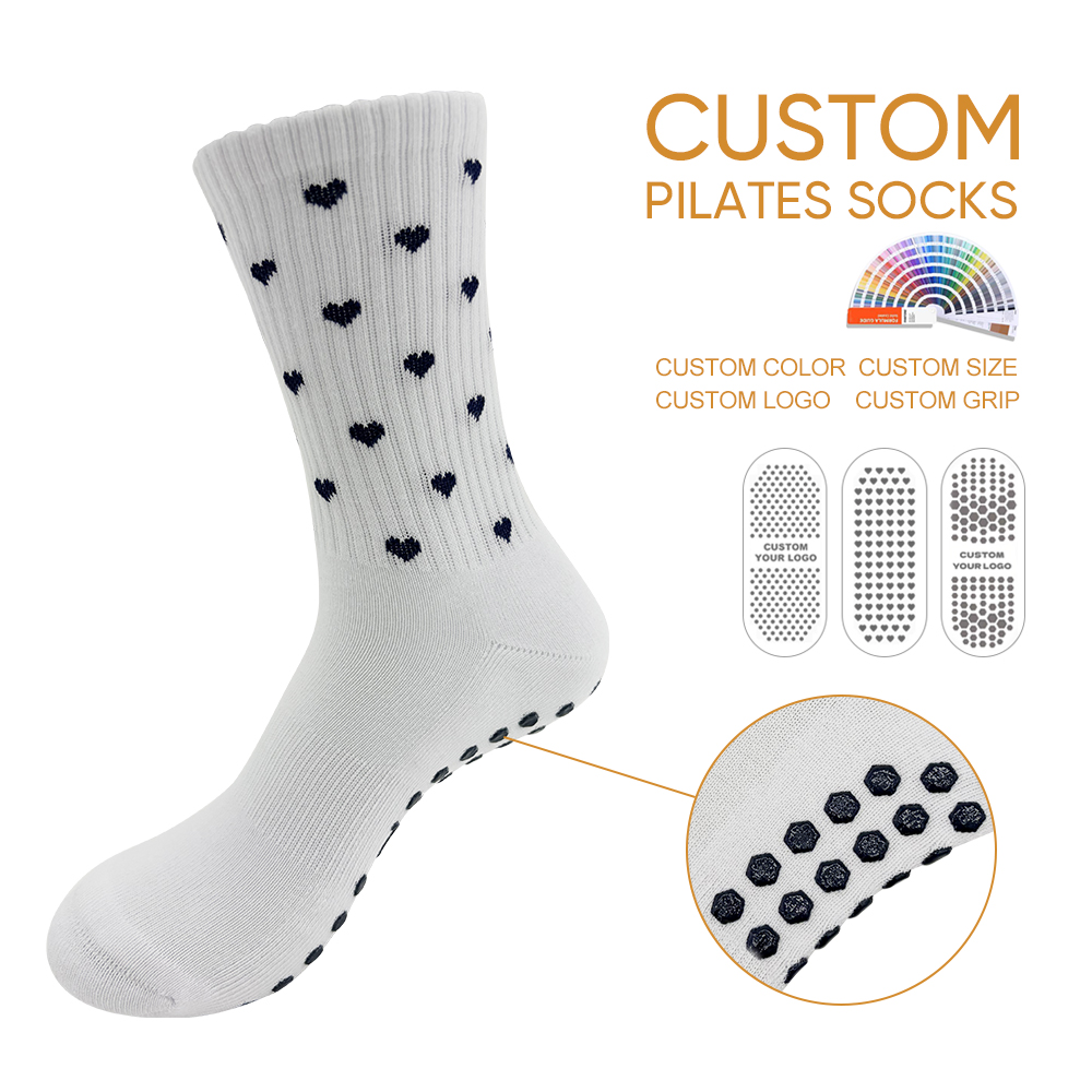 White crew Pilates grip sock with black knitted mini hearts and visible black sole grip dots