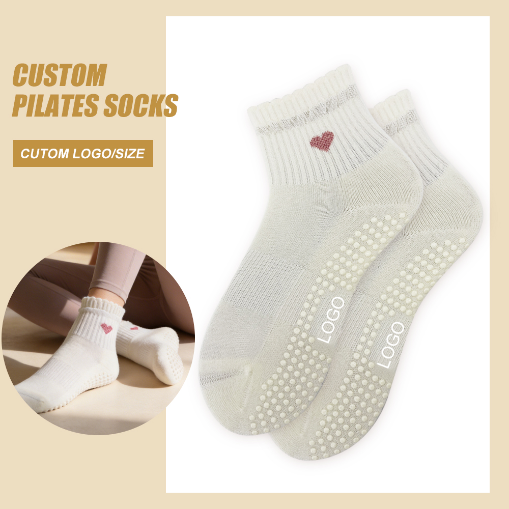 Cream ruffle ankle grip socks with one pink glitter-heart motif and visible full-sole grip dots